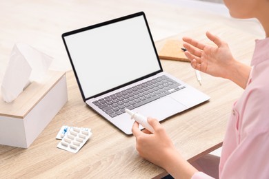 Photo of Sick woman with nasal spray having online consultation with doctor via laptop at wooden table indoors, closeup