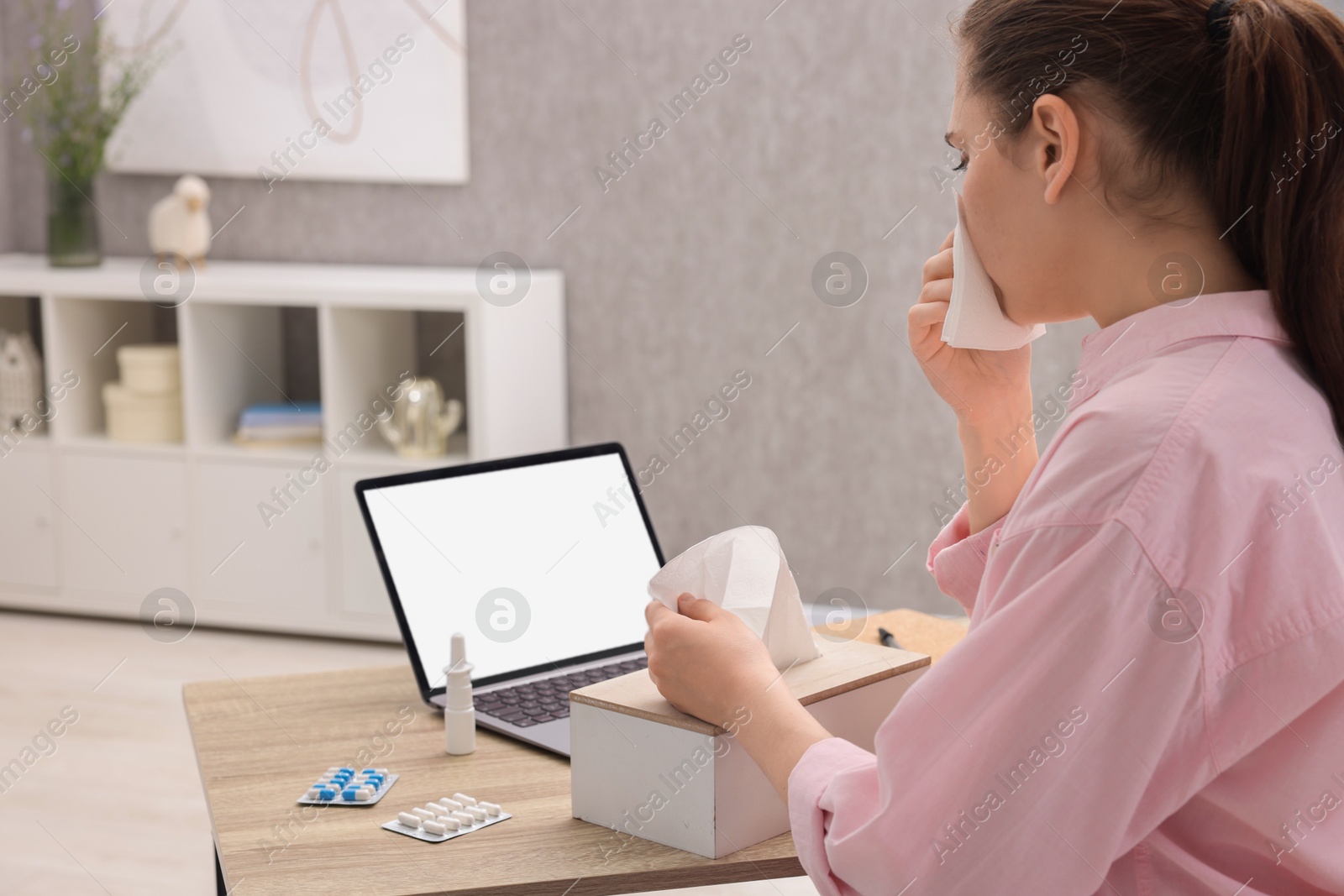 Photo of Sick woman having online consultation with doctor via laptop at wooden table indoors