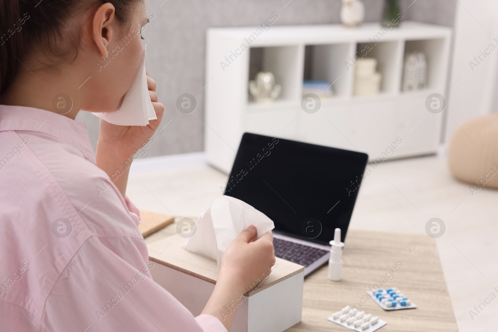 Photo of Sick woman having online consultation with doctor via laptop at wooden table indoors