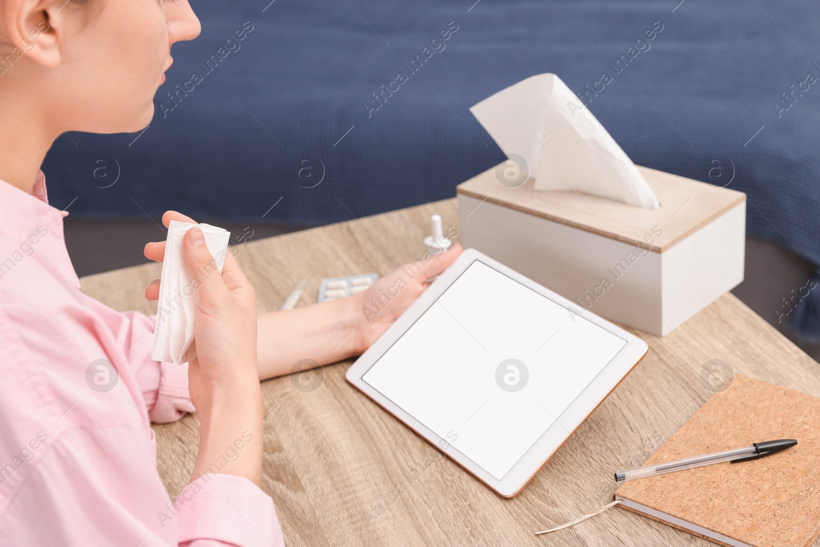 Photo of Sick woman having online consultation with doctor via tablet at wooden table indoors, closeup