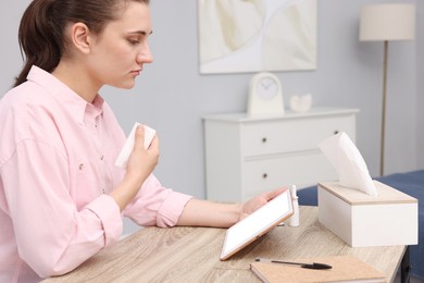 Photo of Sick woman having online consultation with doctor via tablet at wooden table indoors