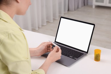 Photo of Sick woman having online consultation with doctor via laptop at white table indoors, closeup