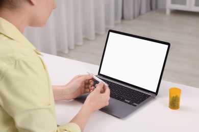 Sick woman having online consultation with doctor via laptop at white table indoors, closeup