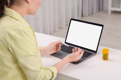 Sick woman having online consultation with doctor via laptop at white table indoors, closeup