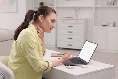 Sick woman having online consultation with doctor via laptop at white table indoors