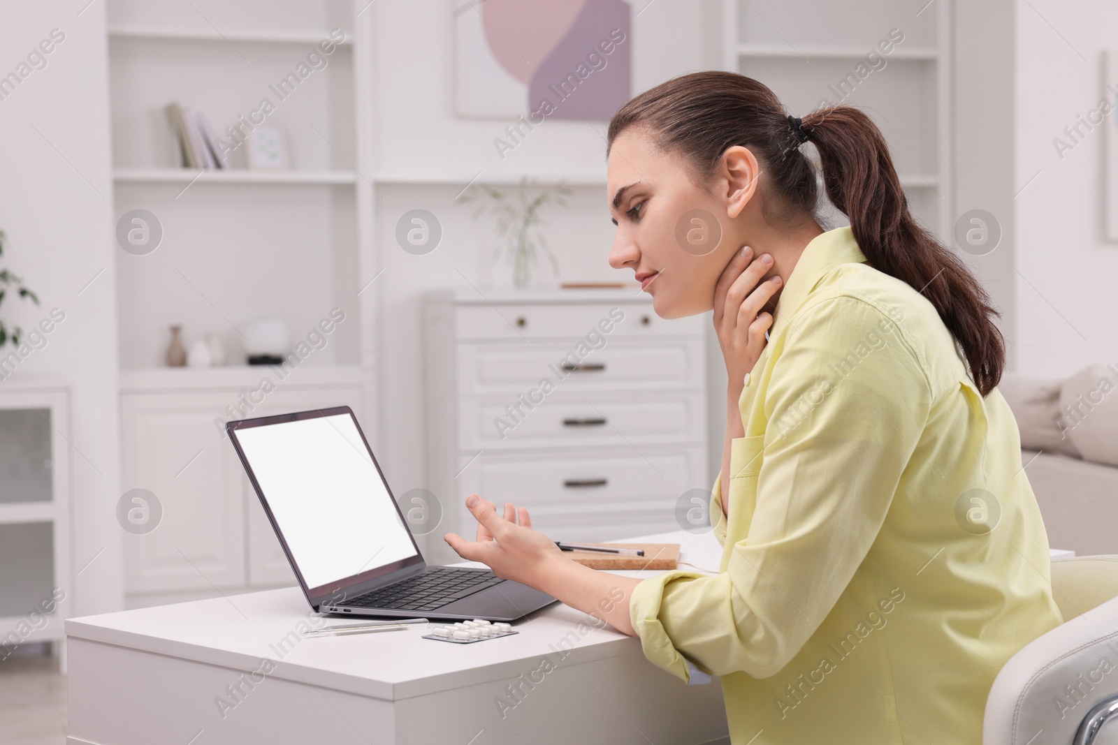 Photo of Sick woman having online consultation with doctor via laptop at white table indoors