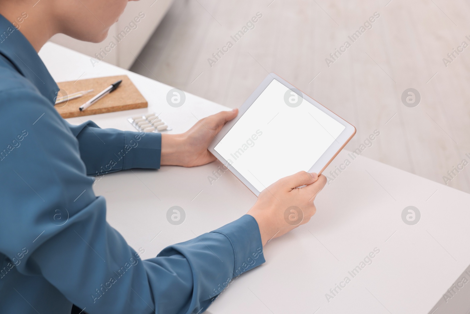 Photo of Sick woman having online consultation with doctor via tablet at white table indoors, closeup