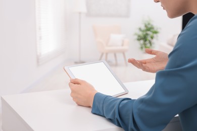 Photo of Sick woman having online consultation with doctor via tablet at white table indoors, closeup