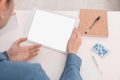 Photo of Sick woman having online consultation with doctor via tablet at white table indoors, closeup