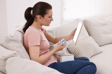 Sick woman with pills having online consultation with doctor via tablet at home