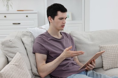 Sick man having online consultation with doctor via tablet at home