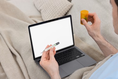 Photo of Sick man with pills having online consultation with doctor via laptop at home, closeup