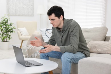 Photo of Sick man having online consultation with doctor via laptop at white table indoors