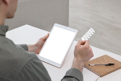 Sick man with pills having online consultation with doctor via tablet at home, closeup