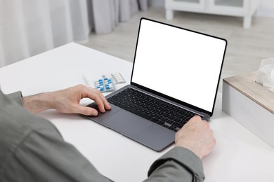 Sick man having online consultation with doctor via laptop at white table indoors, closeup