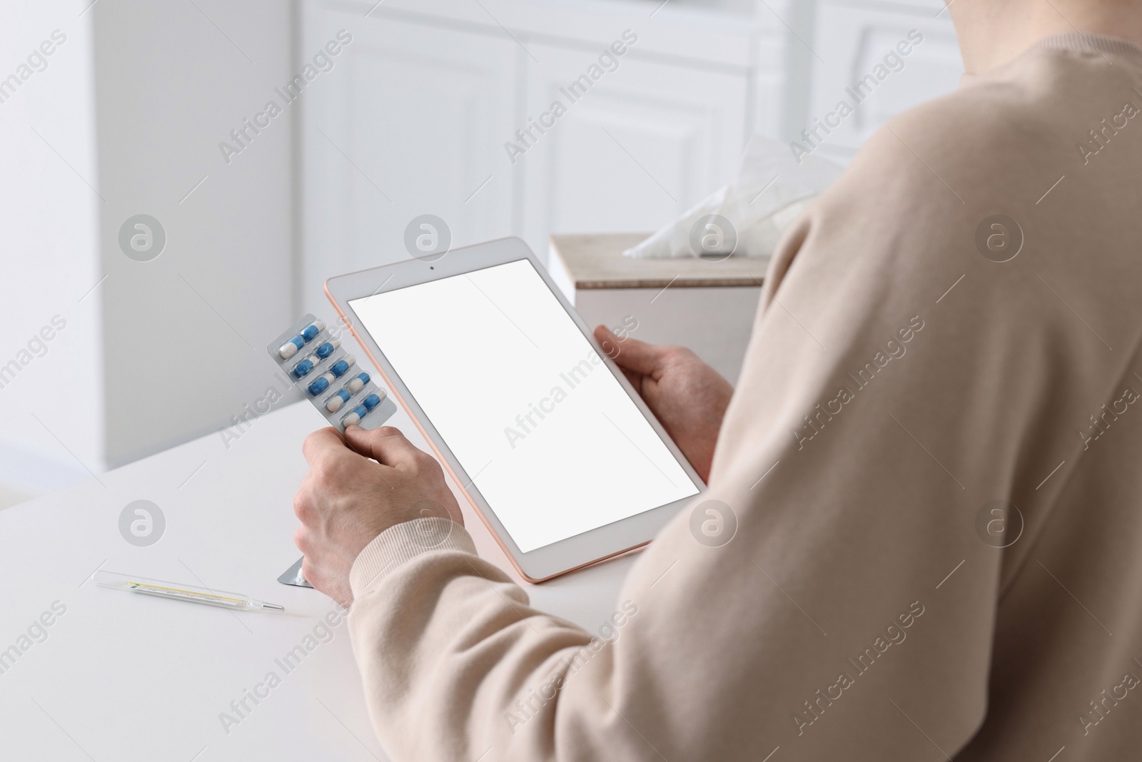 Photo of Sick man having online consultation with doctor via tablet at white table indoors, closeup