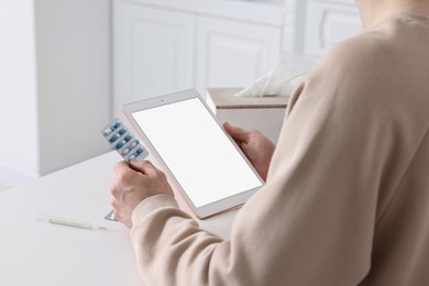 Photo of Sick man having online consultation with doctor via tablet at white table indoors, closeup