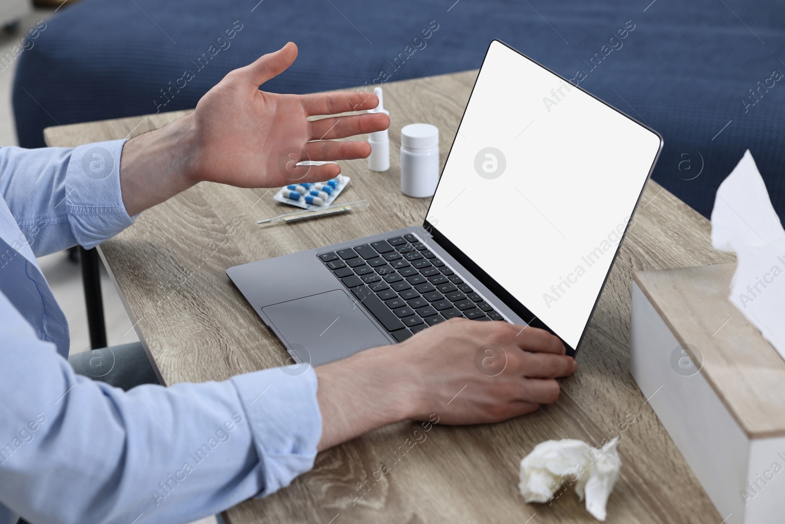 Photo of Sick man having online consultation with doctor via laptop at wooden table indoors, closeup