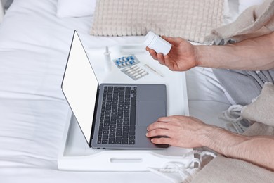 Photo of Sick man with pills having online consultation with doctor via laptop at home, closeup