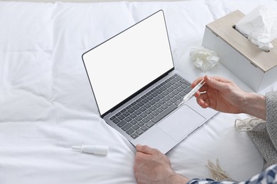 Photo of Sick man with thermometer having online consultation with doctor via laptop at home, closeup