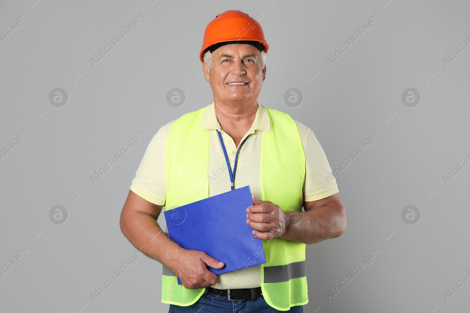 Photo of Engineer in hard hat with clipboard on grey background