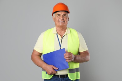 Engineer in hard hat with clipboard on grey background