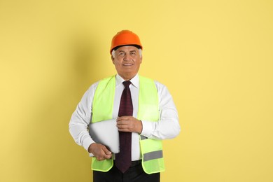 Photo of Engineer in hard hat with laptop on yellow background