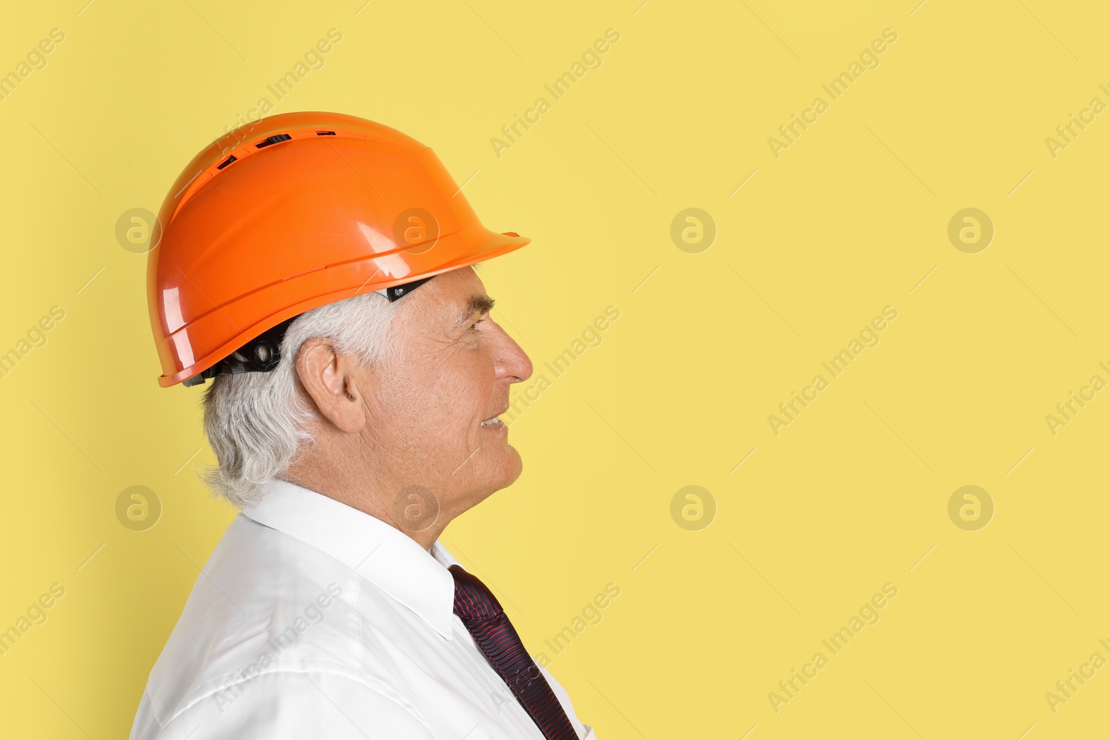 Photo of Engineer in hard hat on yellow background, space for text