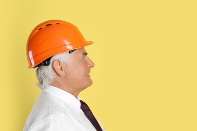 Photo of Engineer in hard hat on yellow background, space for text