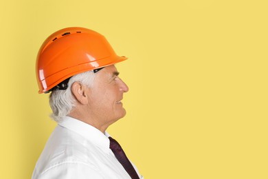 Engineer in hard hat on yellow background, space for text