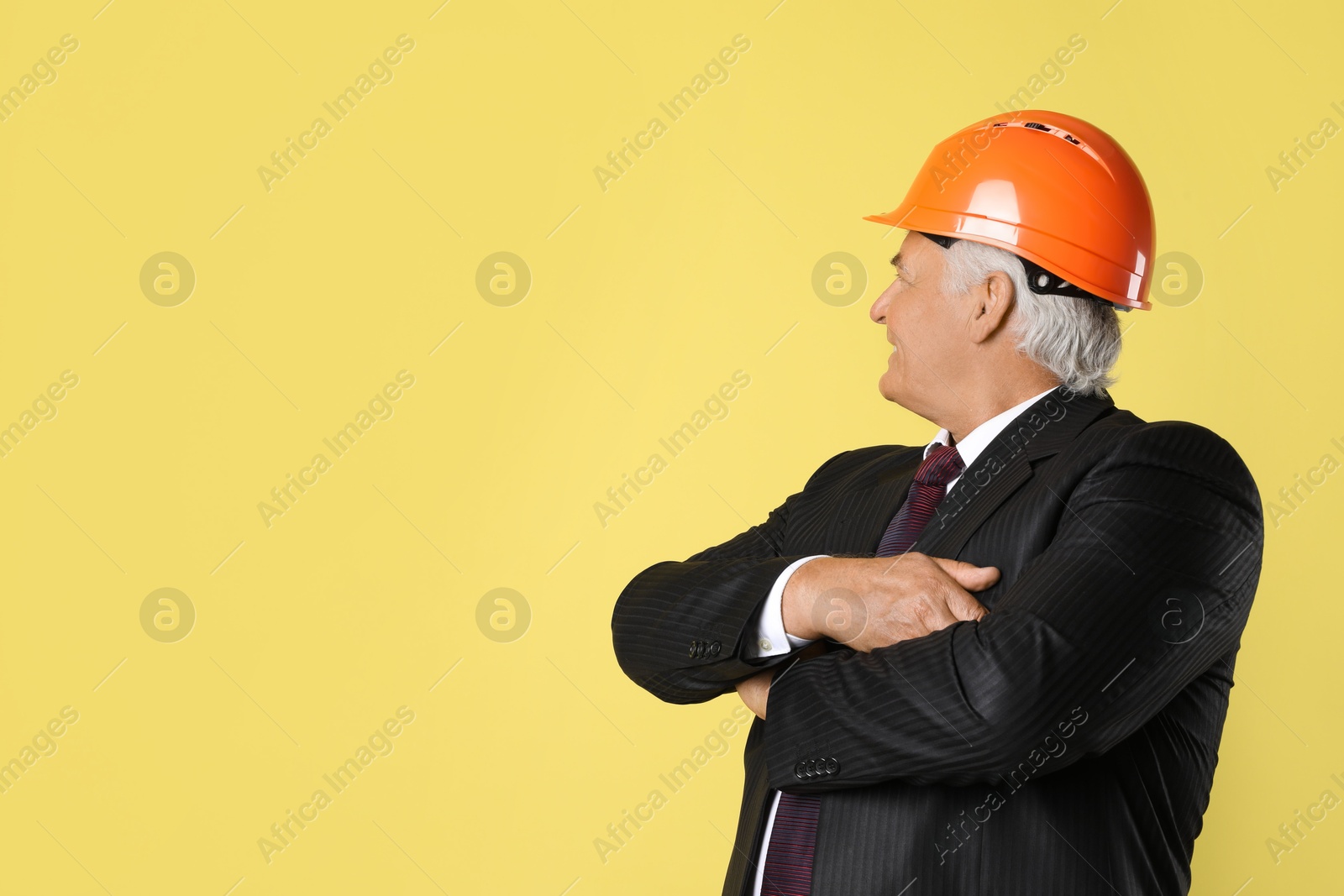 Photo of Engineer in hard hat on yellow background, space for text