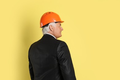 Photo of Engineer in hard hat on yellow background, space for text