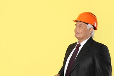 Photo of Engineer in hard hat on yellow background, space for text