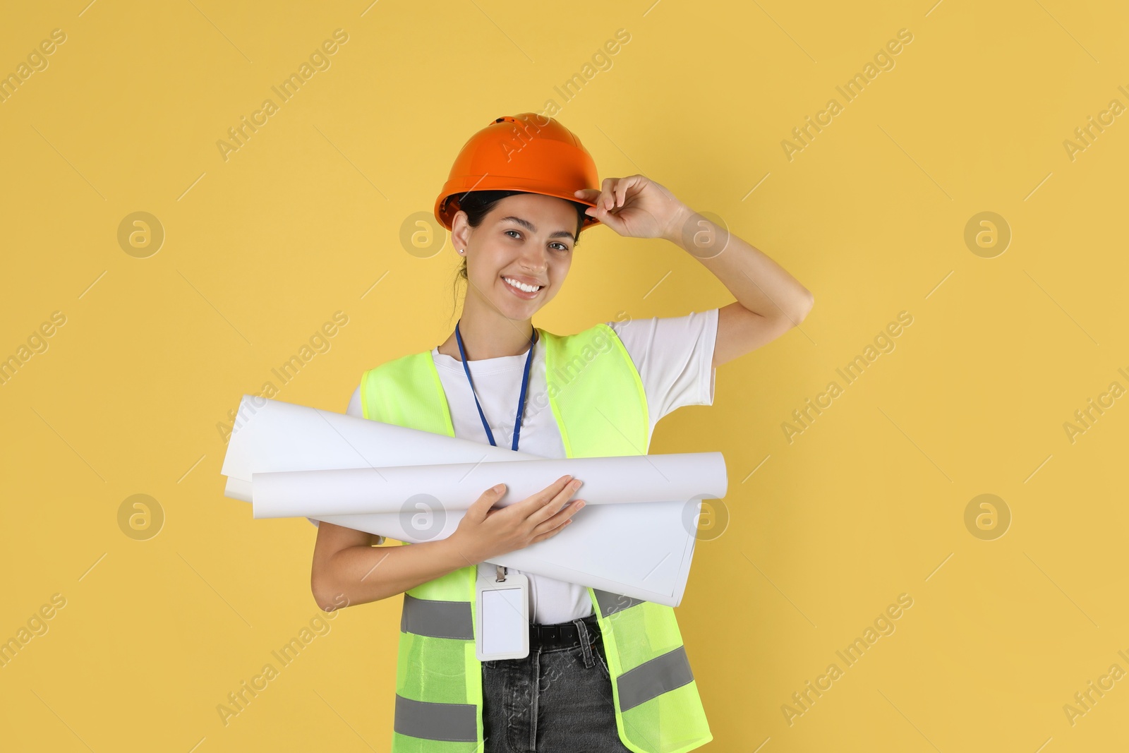 Photo of Engineer in hard hat with drafts on yellow background