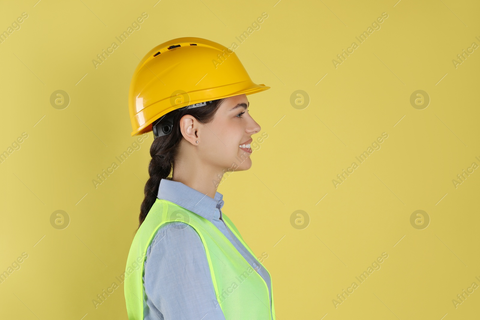 Photo of Engineer in hard hat on yellow background, space for text