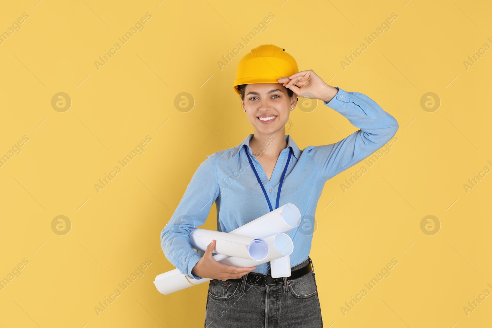 Photo of Engineer in hard hat with drafts on yellow background, space for text