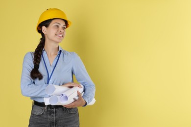 Engineer in hard hat with drafts on yellow background, space for text