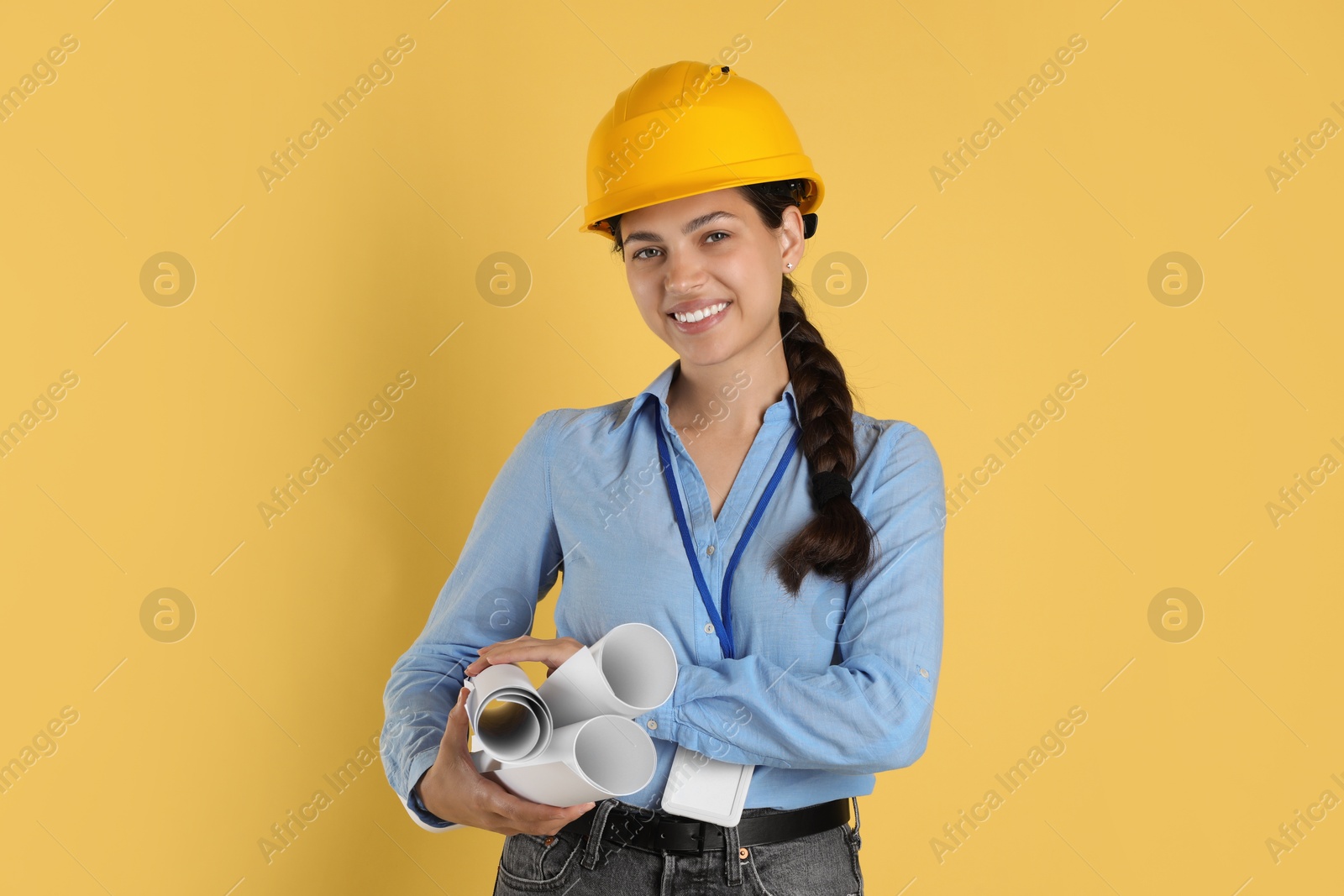 Photo of Engineer in hard hat with drafts on yellow background