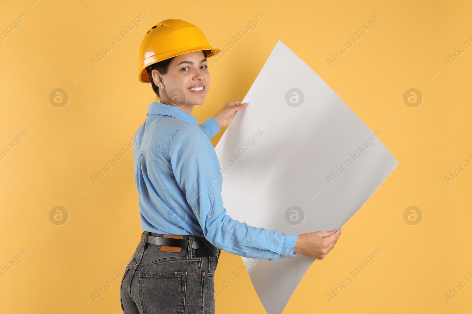 Photo of Engineer in hard hat with draft on yellow background