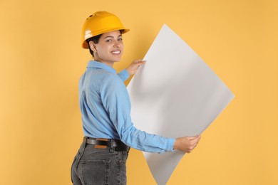 Engineer in hard hat with draft on yellow background