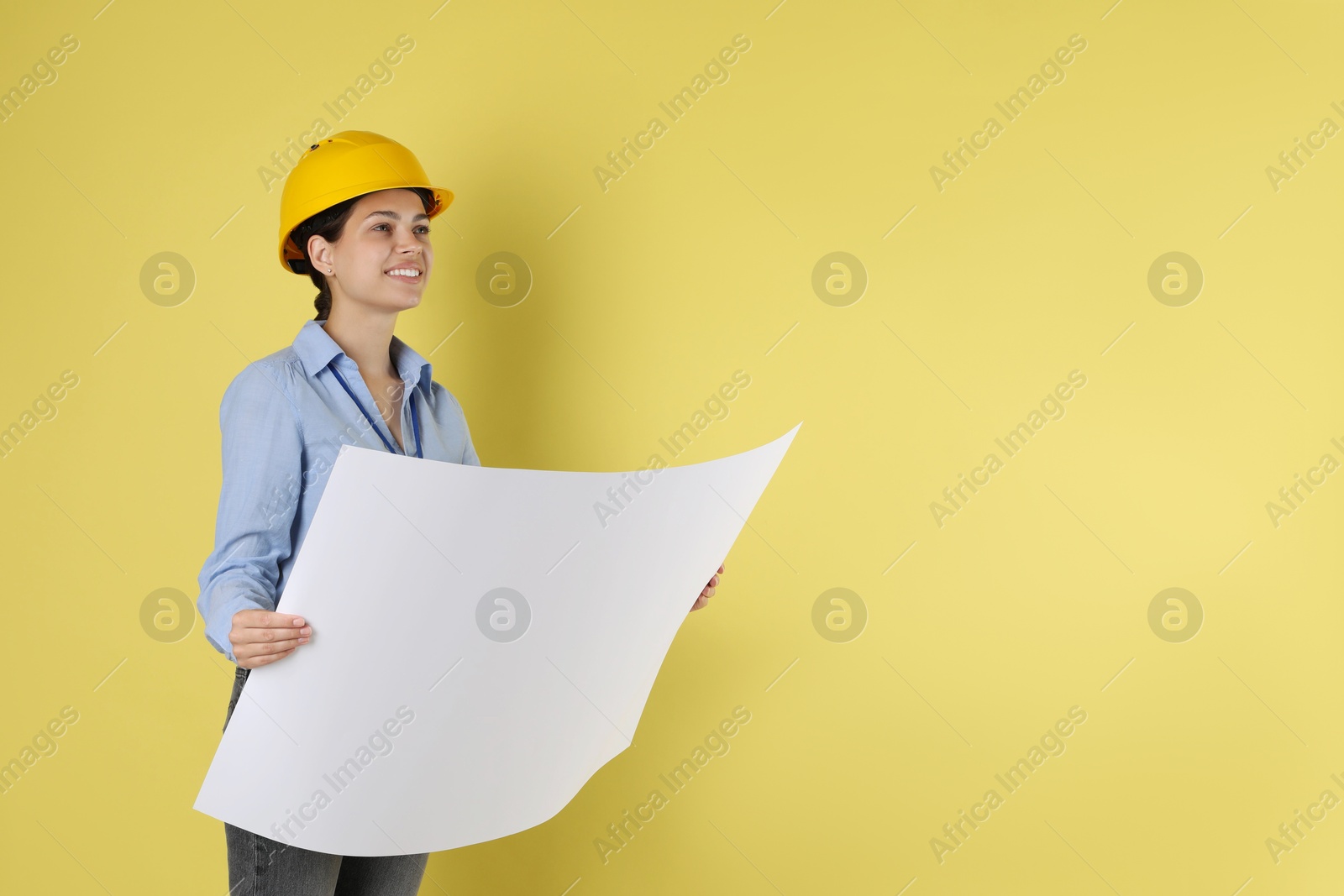 Photo of Engineer in hard hat with draft on yellow background, space for text