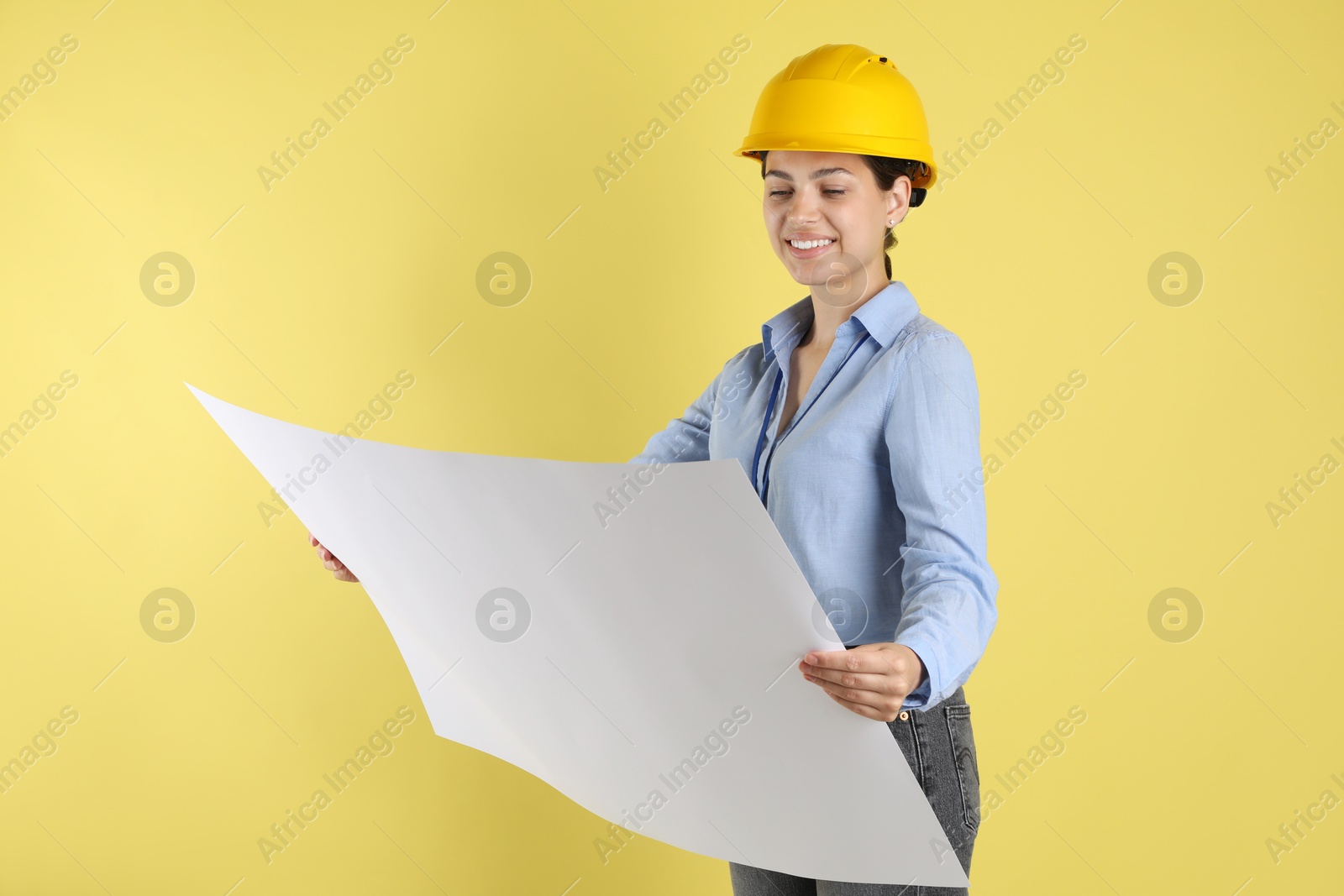 Photo of Engineer in hard hat with draft on yellow background