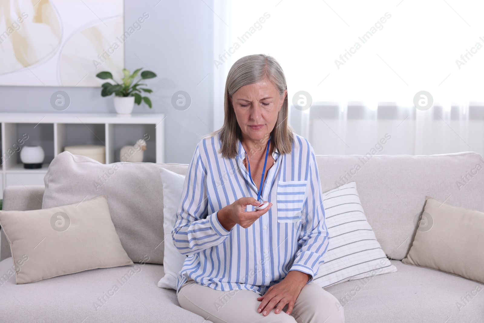 Photo of Senior woman pressing emergency call button at home