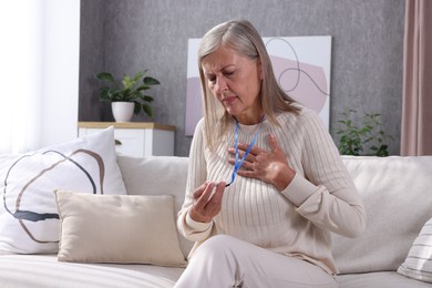 Photo of Senior woman suffering from heart pain holding emergency call button at home