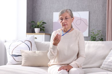 Senior woman in glasses with emergency call button at home