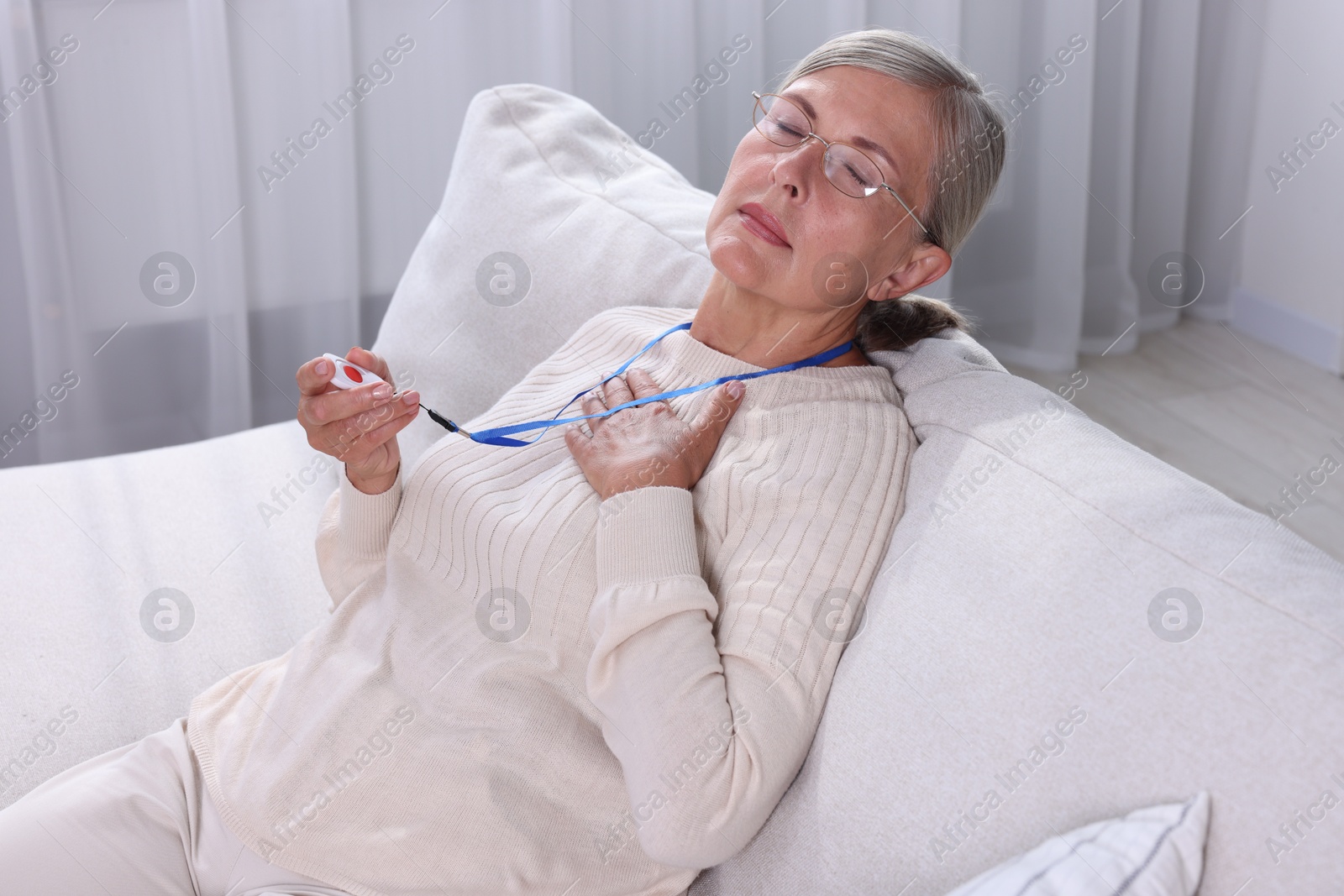 Photo of Senior woman suffering from heart pain holding emergency call button at home