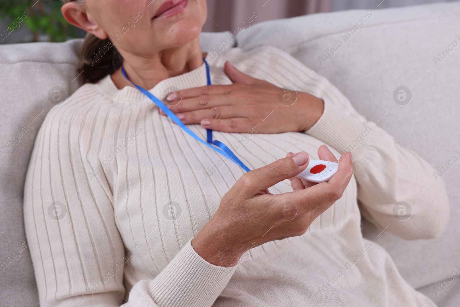 Photo of Senior woman suffering from heart pain holding emergency call button at home