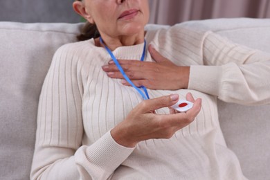 Photo of Senior woman suffering from heart pain holding emergency call button at home