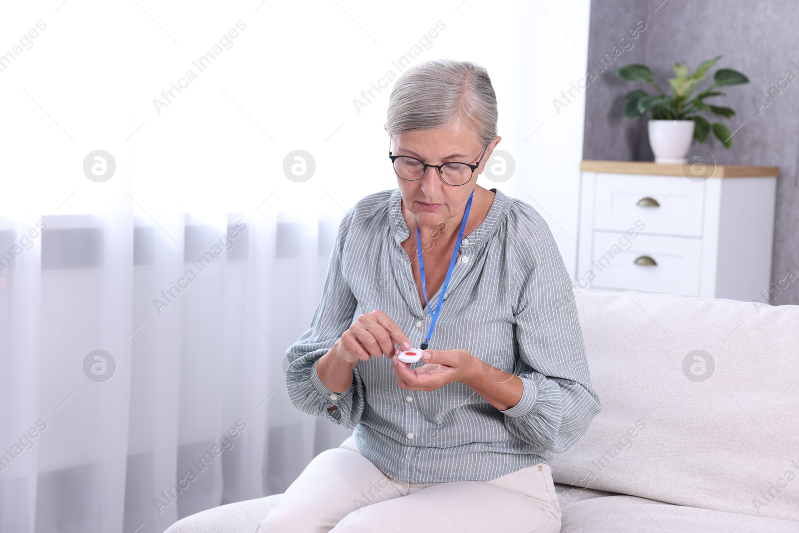 Photo of Senior woman pressing emergency call button at home