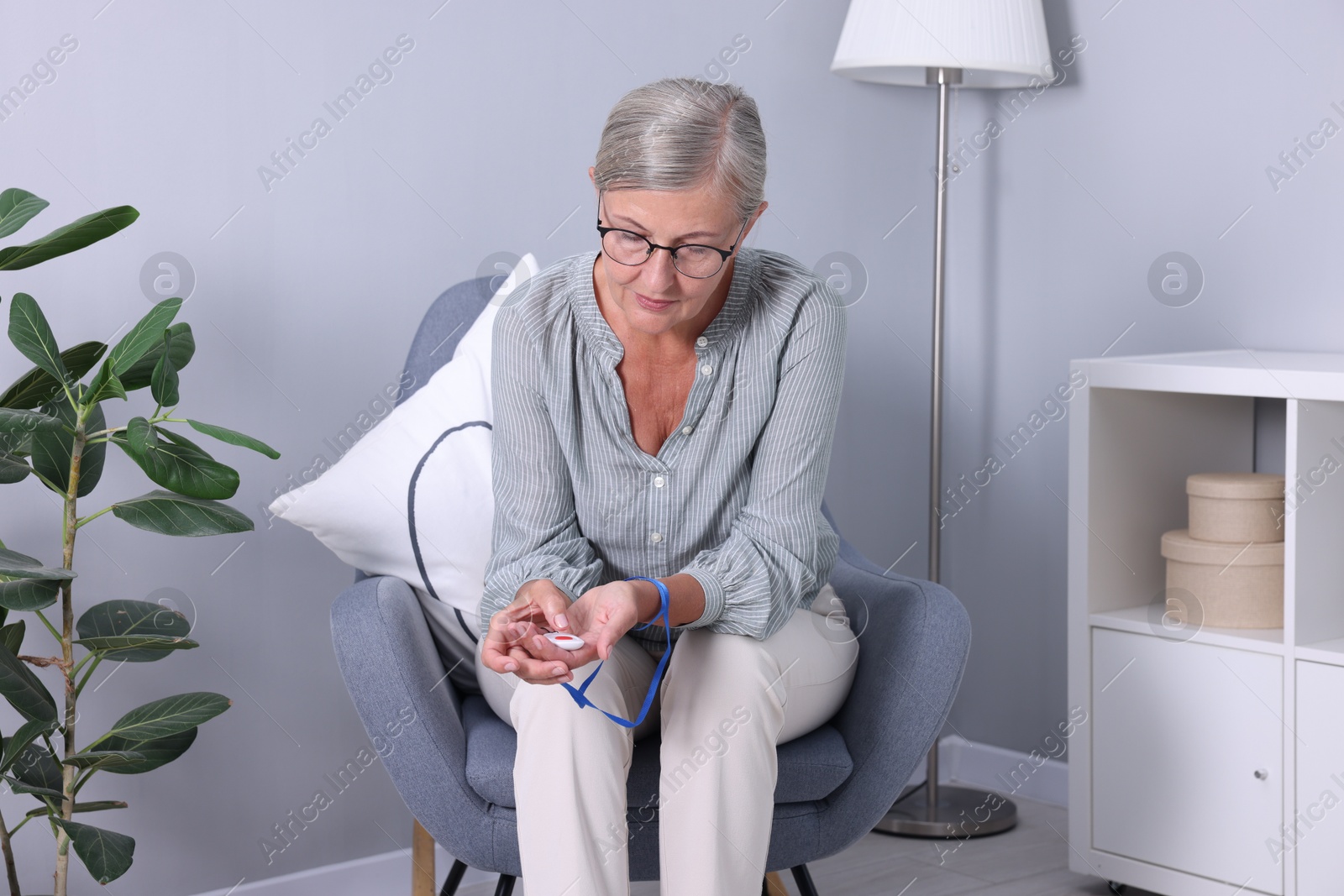 Photo of Senior woman pressing emergency call button at home